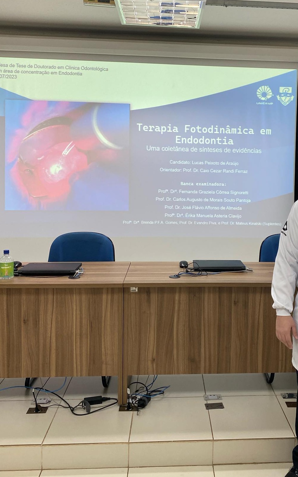 Dr. Lucas Peixoto de Araújo de jaleco e gravata durante apresentação em auditório